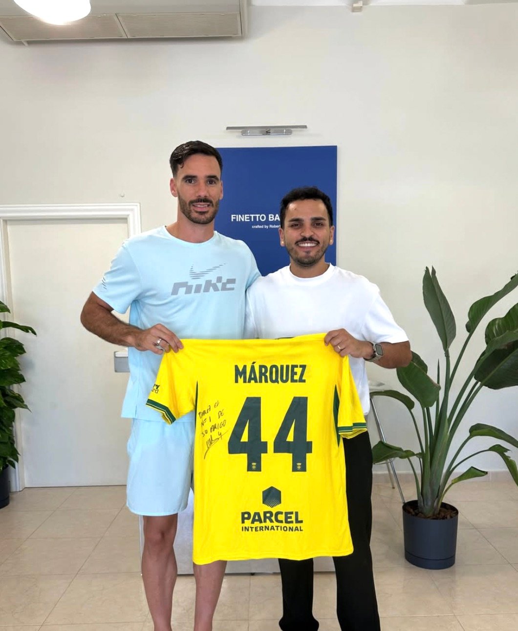 Roberto con un cliente y una camiseta amarilla firmada